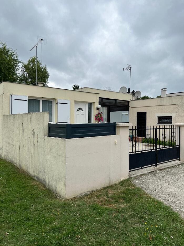 Petite maison avec portail noir et mur à nettoyer