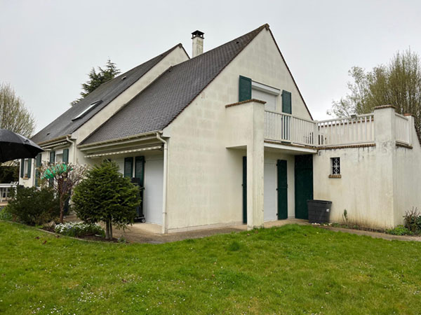 Maison avec vue sur un mur qui laisse apparaître des parpaings sous le crépi