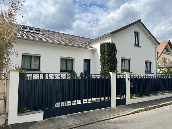 Vue d'une façade de maison avec clôture métallique noire après ravalement