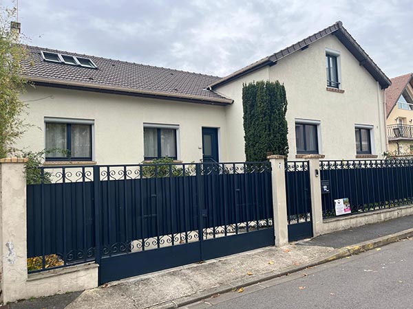 Vue d'une façade de maison avec clôture métallique noire
